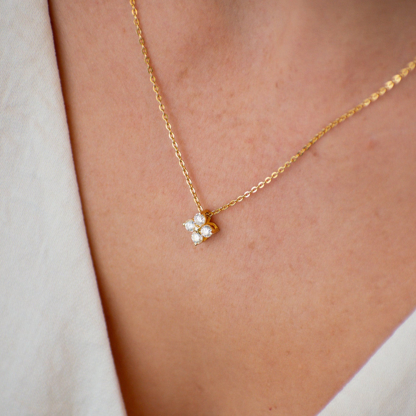 Gold necklace with a small pendant on a person wearing a light-colored top.