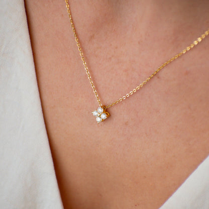 Gold necklace with a small pendant on a person wearing a light-colored top.