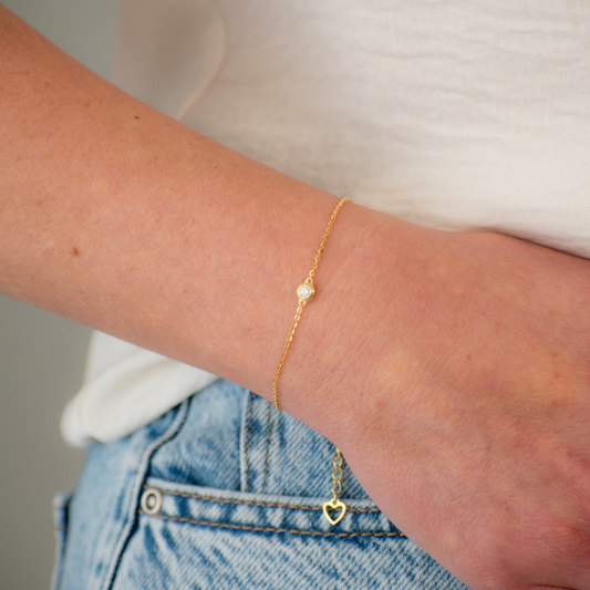 Gold bracelet on a wrist with a neutral background